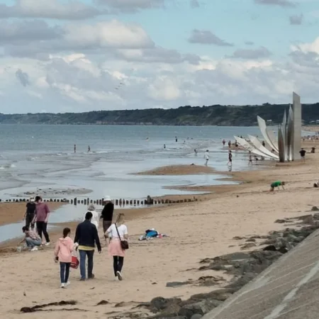 Visitantes recorriendo las playas de Normandía en la actualidad, una experiencia de turismo cultural y viajes de historia para descubrir los escenarios y el patrimonio de la Segunda Guerra Mundial.