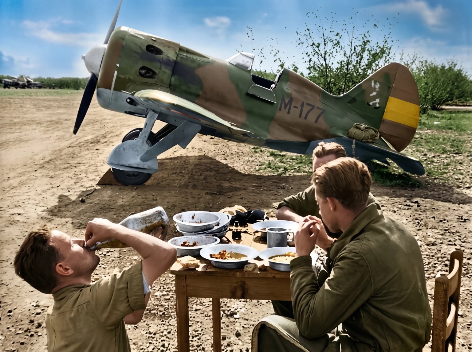 Pilotos republicanos disfrutando de una comida junto a un caza Polikarpov durante la Guerra Civil Española, imagen histórica de aviación militar, vida cotidiana en el frente y descanso de combatientes republicanos